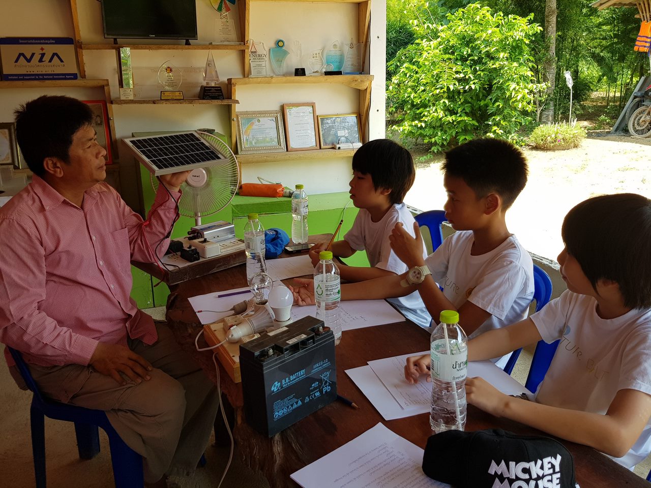 Students learning about renewable energy from Koson Saengthong at Pa Deng Village